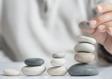 Man stacking pebbles on table