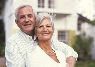 Senior Couple Smiling in Front of House