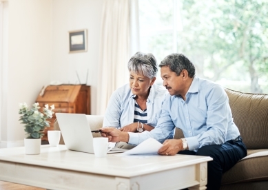 Senior Couple Discussing Something on Couch with Laptop in Front of Them